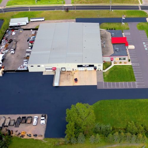 Wide aerial view of Holz Builders' parking lot in Wisconsin Dells, WI, featuring fresh sealcoating and organized parking spaces.